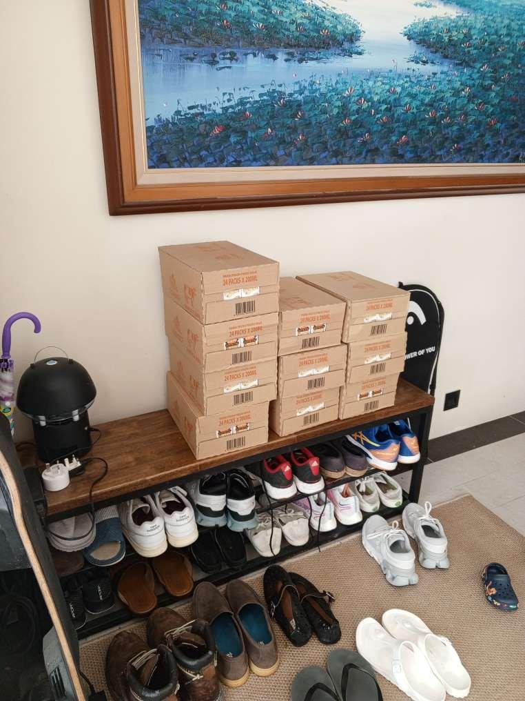Farm Fresh pouch milk boxes stacked on a home entryway shoe rack.